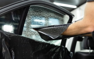 technician applying window tint to car passenger window